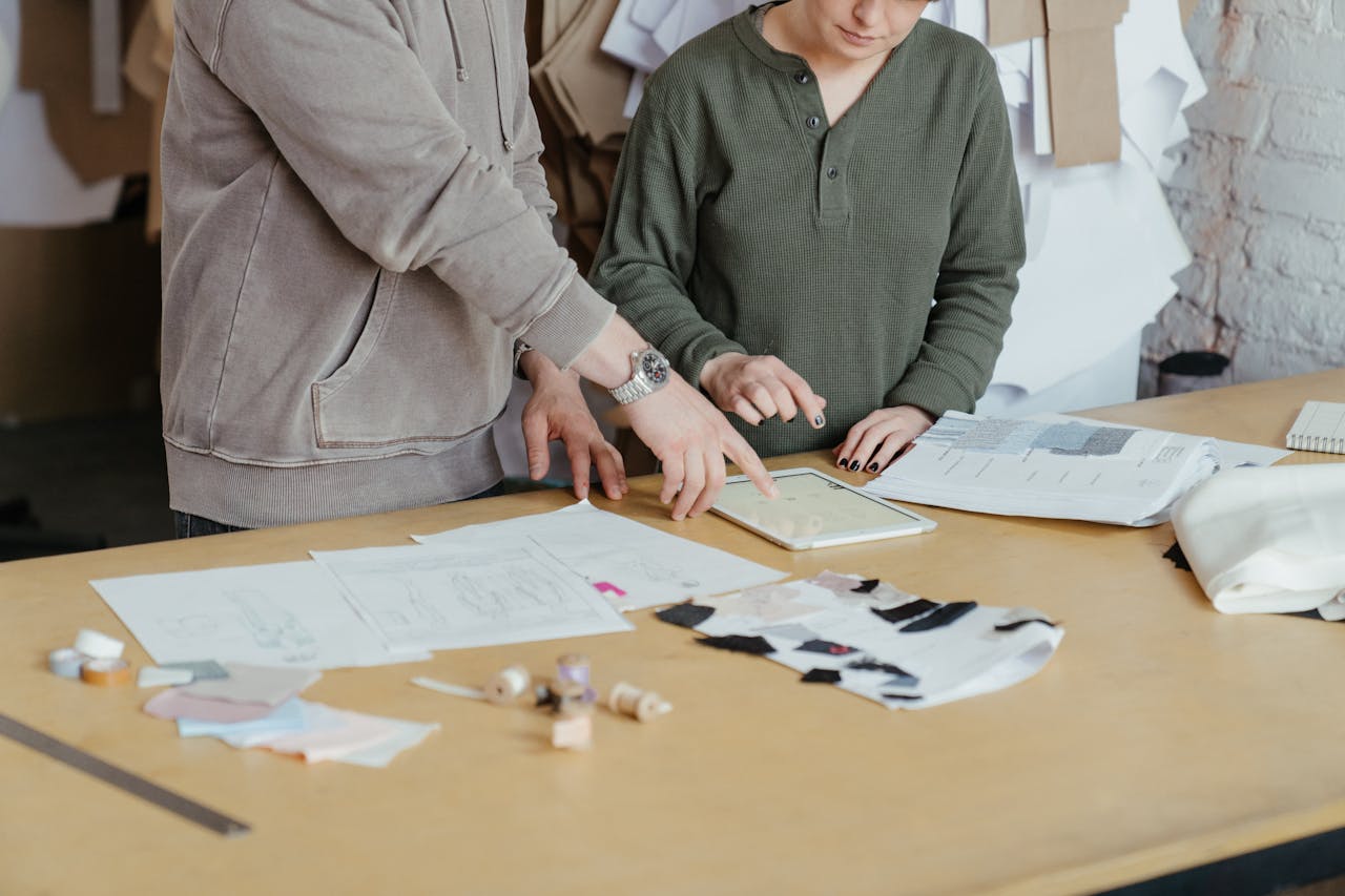 Fashion designers using digital tools and fabric samples in a creative workshop setting.